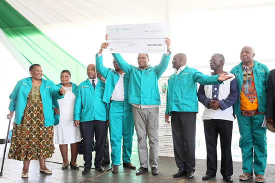 MEC Cyril Xaba holds a R34 million cheque to be shared between various cooperatives in the Harry Gwala Municipality.