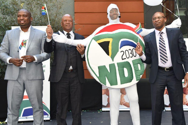 Deputy Minister Buti Manamela, Minister Jeff Radebe and Acting Director-General Tshediso Matona with the NDP mascot showing off the new logo.