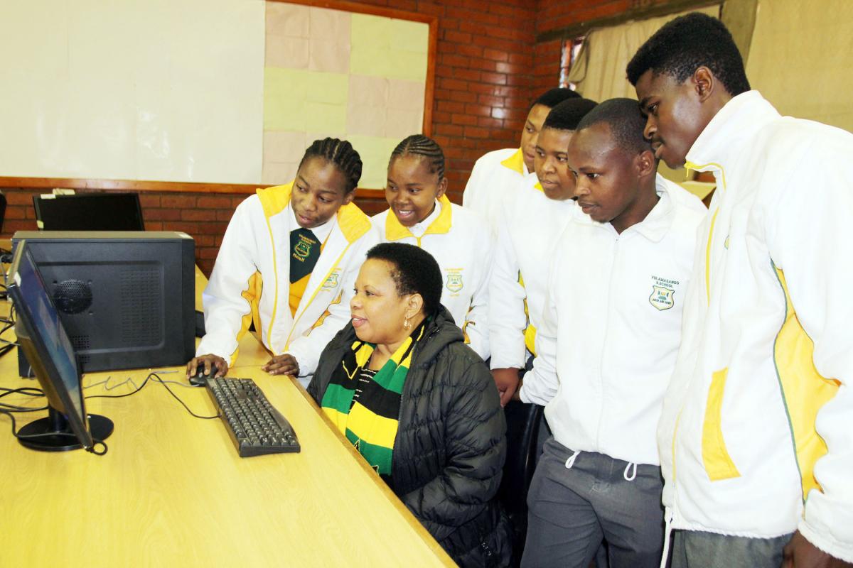 Deputy Minister Maggie Sotyu and learners at Vulamasango High School try out one of the new computers.