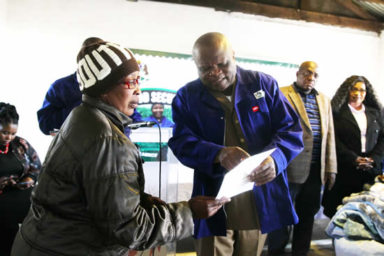 MEC for Agriculture and Rural Development Themba Mthembu hands over one of 67 food vouchers to one of 67 families in Greytown. (Photo: KZNDARD)