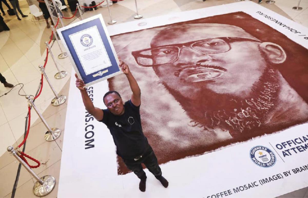 Artist Percy Maimela holds his certificate from Guinness World Records after creating a mosaic out of ground coffee beans of artist Black Coffee