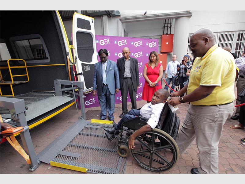 Former eThekwini Municipality Speaker Cllr Logie Naidoo, ETA’s Shoneeze Franks (in red) and Logan Moodley watch as driver Mfanafuthi Ngcobo and Dial-A-Ride user Sboniso Dlamini demonstrate how the lift of one of the new GO!Durban Dial-A-Ride buses works.