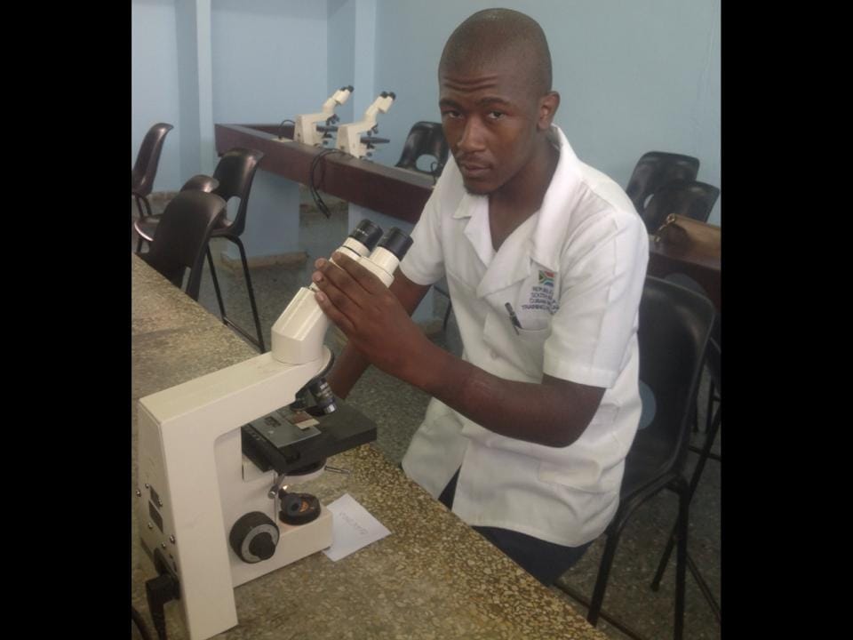 Zazi Zulu using a microscope during his studies in Cuba
