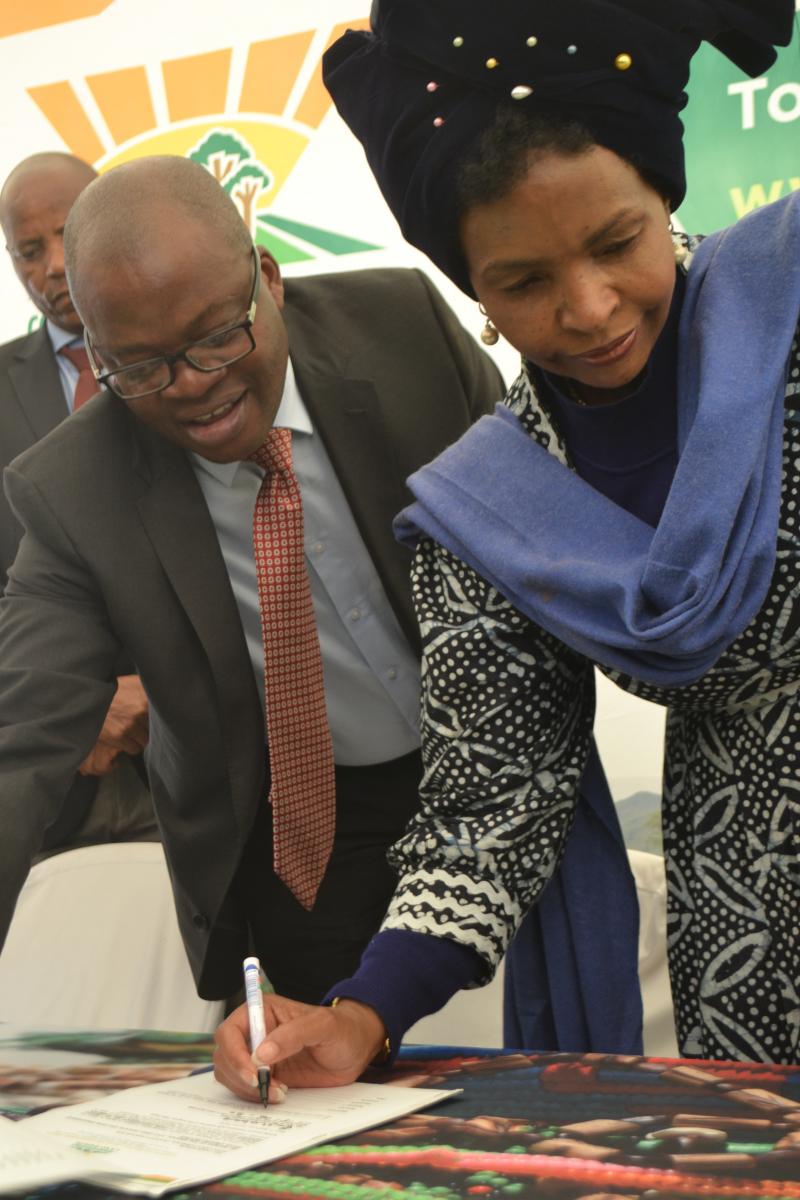 Chief Director of Land Restitution Support in Limpopo Commissioner Tele Maphoto assisting Minister of Rural Development and Land Reform Maite Nkoana-Mashabane as she signs the title deed.