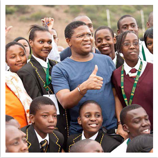Minister Fikile Mbalula interacts with a group of learners during a school sports event.