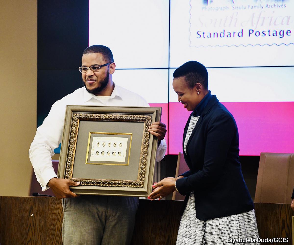 Communications Minister Stella Ndabeni-Abrahams hands over the centenary commemorative stamp of Albertina Sisulu to the struggle icon’s grandson Duma Sisulu.