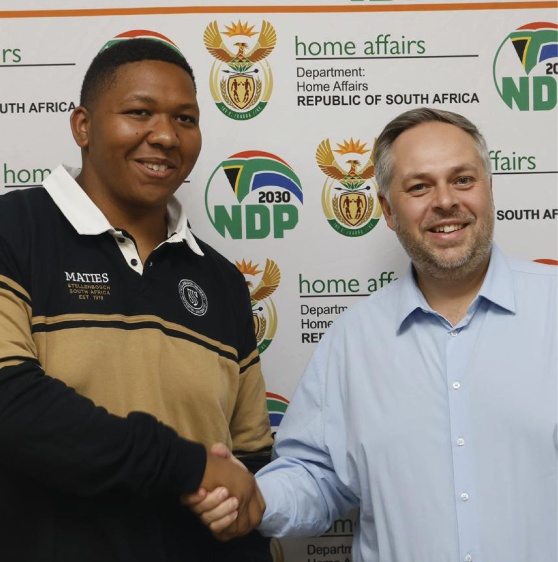 Home Affairs Minister Leon Schreiber hands over the first Smart ID containing a traditional Khoikhoi name to student !Khūboab Lawrence who is Lesle Jansen’s son.