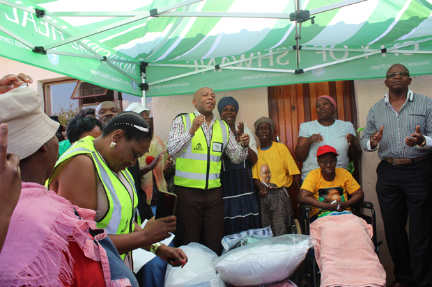 Mayor of Tshwane Kgosientso Ramokgopa dances at the hand over of a newly built house in Ekangala as recipient, Poppy Mabena (in a red cap) looks on.