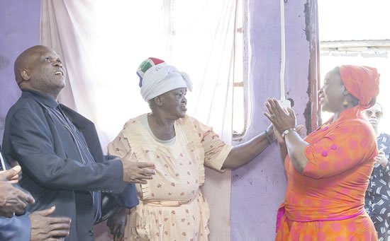 Eighty-four-year-old Thobekile Mkhize turns on the lights in her Magogo Village home, as MEC Themba Mthembu (left) and MEC Nomusa Dube-Ncube look on. (Image: KZN CoGTA)