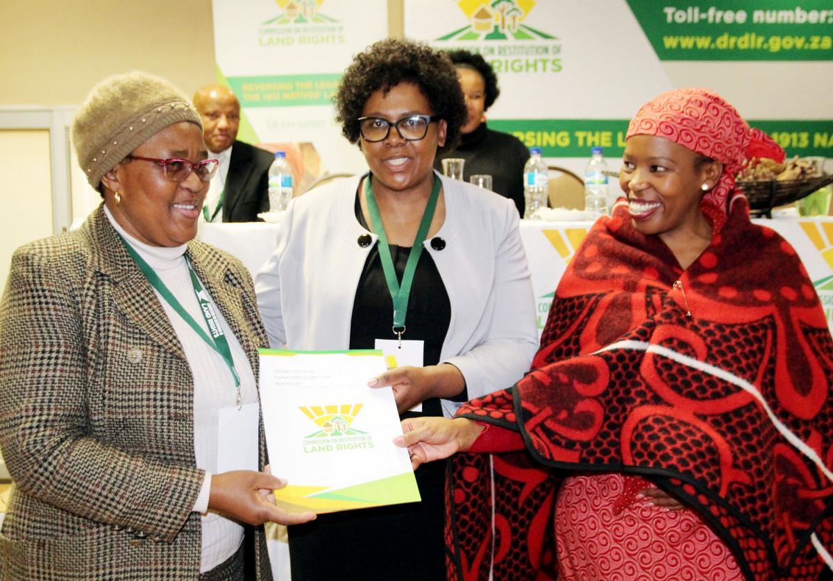 Keneilwe Goronyane shows the deed to her land to the chief commissioner of land claims Nomfundo Ntloko-Gobodo and Queen Thato Mopeli.