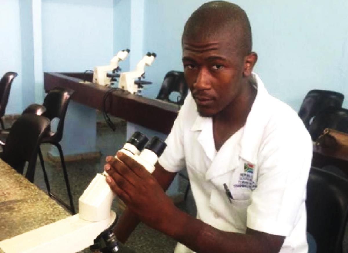 Zazi Zulu using a microscope during his studies in Cuba.