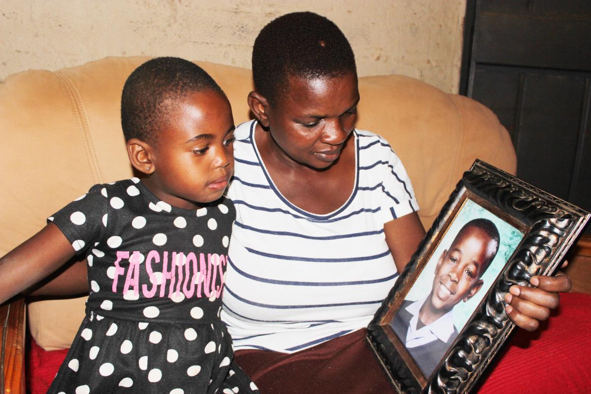 Sarah Tambani and her grandchild, eight-year-old Tshiamo, looking at a picture of her late son Thapelo who received the National Order of Mendi for Bravery.