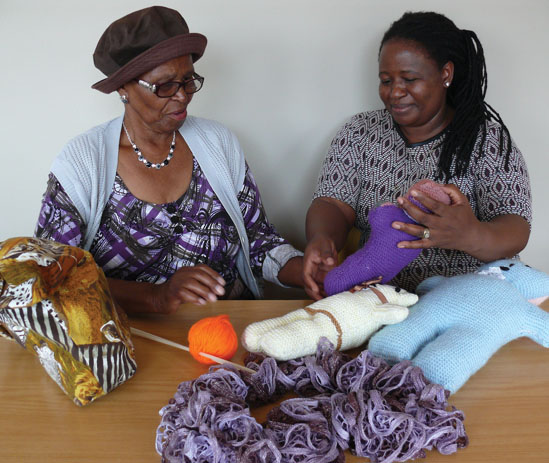 Zamokuhle beneficiary Victoria Smith and social worker student Makgati Legodi have a look at the latest teddies knitted by the gogos.