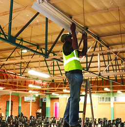 An employee from GreenX Engineering replacing fluorescent lights with energy-saving lights at a Western Cape school.