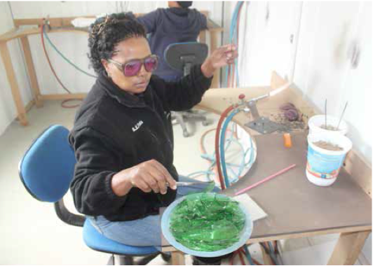 Photo caption: Nolwazi Maphumulo, one of the members of Simunye Hand Craft and Jewellery, demonstrates how they turn their trash into treasure by converting crushed glass to jewellery.