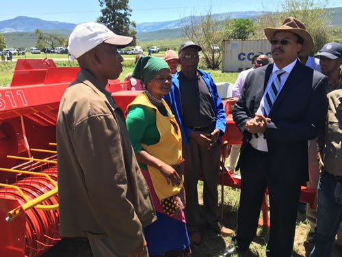 MEC Mlibo Qoboshiyane with beneficiaries of the drought relief programme standing in front of the equipment donated by the Department of Rural Development and Agrarian Reform.